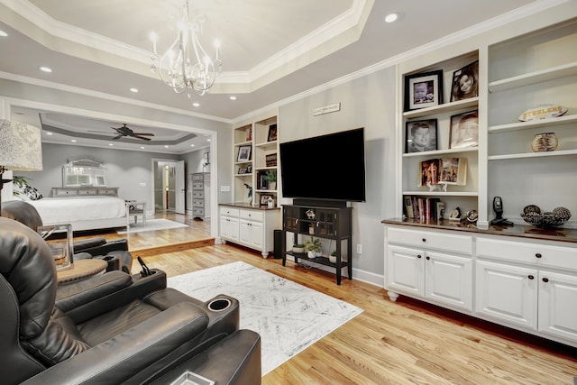 living room featuring ceiling fan with notable chandelier, light hardwood / wood-style floors, a raised ceiling, and ornamental molding