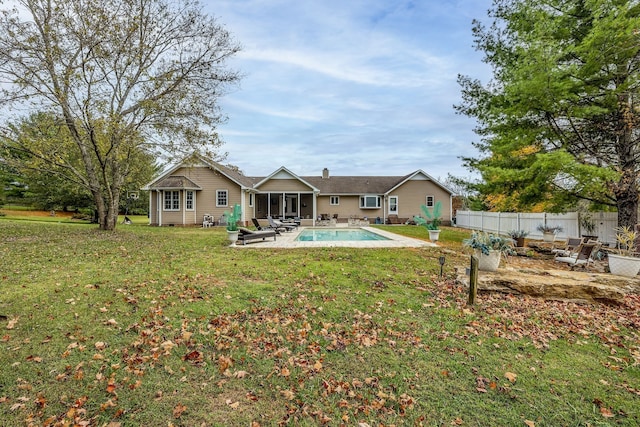 back of house with a sunroom, a fenced in pool, a patio area, and a lawn