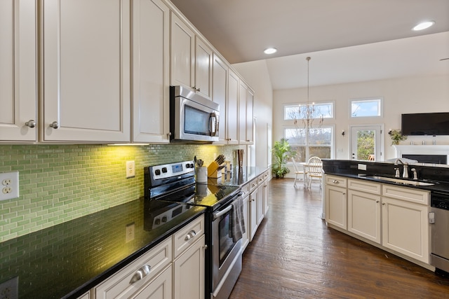 kitchen with appliances with stainless steel finishes, dark wood-type flooring, sink, pendant lighting, and a chandelier