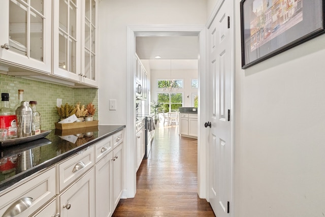 bar with white cabinets, backsplash, dark wood-type flooring, and dark stone counters