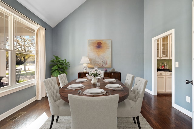 dining room with high vaulted ceiling and dark wood-type flooring