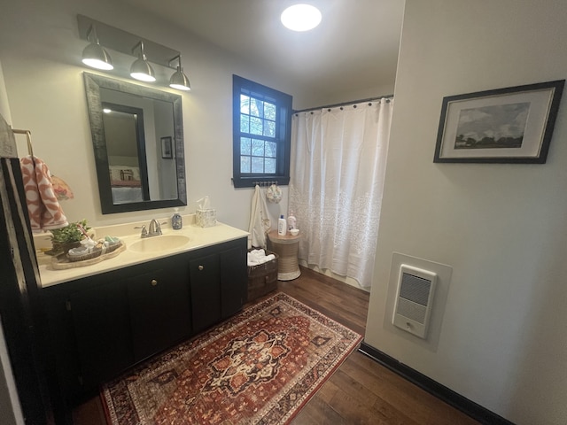 bathroom with heating unit, vanity, and hardwood / wood-style flooring