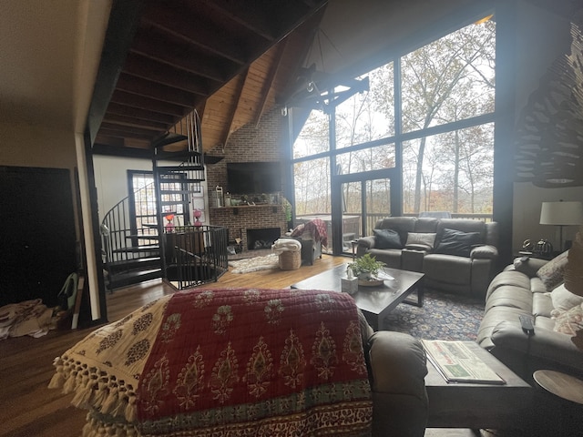 living room with wood-type flooring, high vaulted ceiling, plenty of natural light, and a brick fireplace