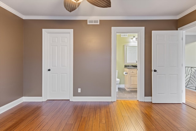 unfurnished bedroom with crown molding, ensuite bath, wood-type flooring, and ceiling fan