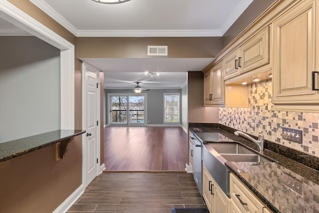 kitchen featuring dark stone countertops, crown molding, dark hardwood / wood-style flooring, and stainless steel dishwasher