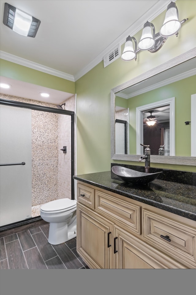 bathroom featuring crown molding, toilet, vanity, and a shower with shower door