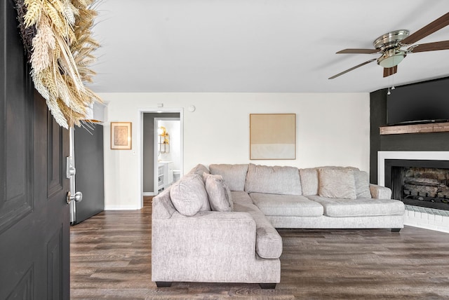 living room with dark hardwood / wood-style flooring, a large fireplace, and ceiling fan