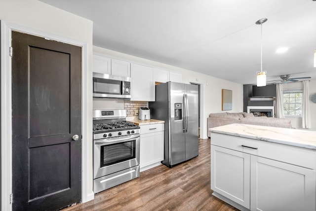 kitchen with pendant lighting, dark hardwood / wood-style floors, appliances with stainless steel finishes, tasteful backsplash, and white cabinetry