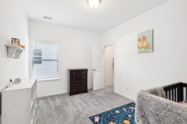 bedroom featuring light colored carpet and a nursery area