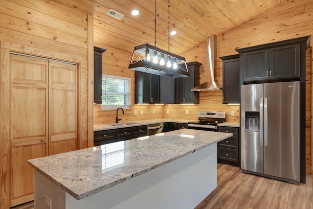 kitchen with wall chimney range hood, a center island, lofted ceiling, and appliances with stainless steel finishes