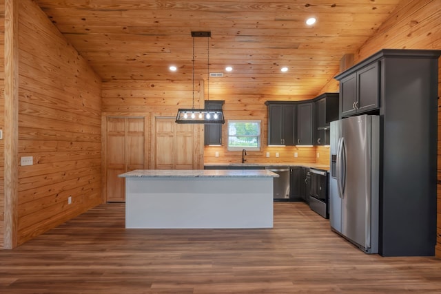 kitchen with lofted ceiling, a kitchen island, decorative light fixtures, and appliances with stainless steel finishes