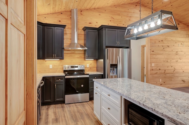 kitchen featuring wall chimney exhaust hood, stainless steel appliances, hanging light fixtures, and vaulted ceiling