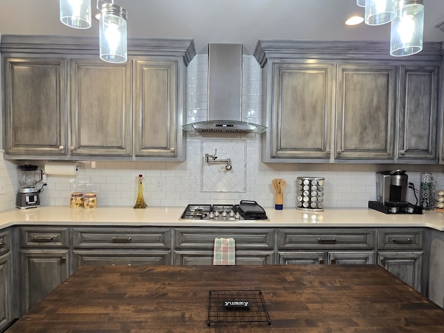 kitchen with stainless steel gas stovetop, wall chimney exhaust hood, and decorative backsplash