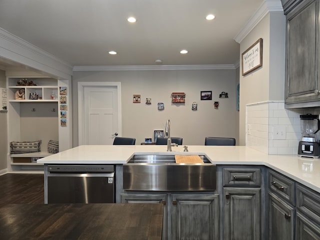 kitchen with stainless steel dishwasher, dark hardwood / wood-style flooring, kitchen peninsula, and sink