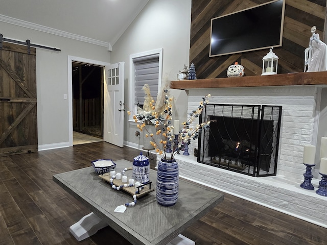 living room with a barn door, a fireplace, dark wood-type flooring, and ornamental molding