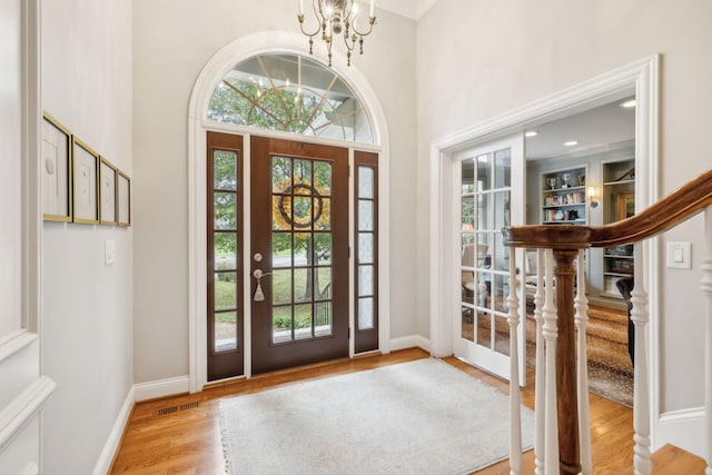 foyer with light wood-type flooring and a notable chandelier