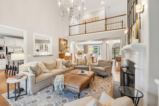 living room with crown molding, a notable chandelier, a high ceiling, and light hardwood / wood-style floors