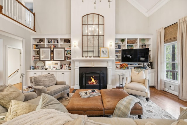 living room with high vaulted ceiling, ornamental molding, and light wood-type flooring