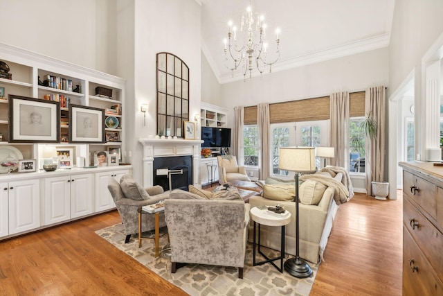 living room featuring high vaulted ceiling, light hardwood / wood-style flooring, ornamental molding, and an inviting chandelier