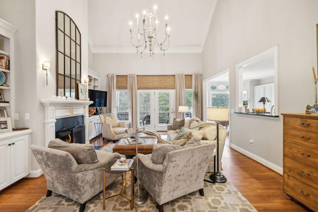 living room with a high ceiling, an inviting chandelier, ornamental molding, and hardwood / wood-style flooring