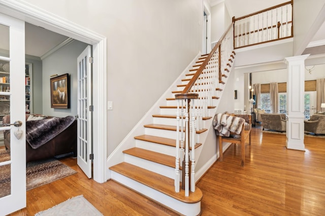 staircase featuring french doors, hardwood / wood-style flooring, ornamental molding, and decorative columns