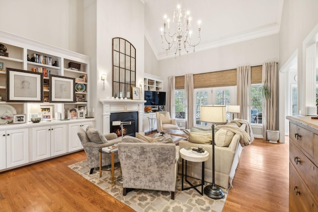 living room with light wood-type flooring, a notable chandelier, and high vaulted ceiling