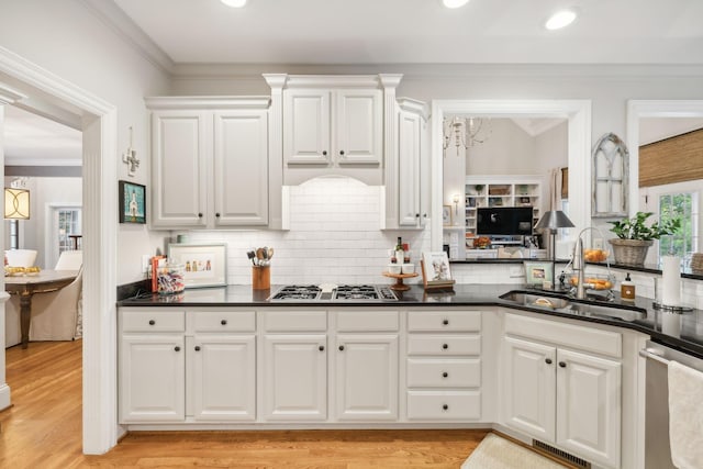 kitchen with light wood-type flooring, white cabinetry, stainless steel appliances, and backsplash