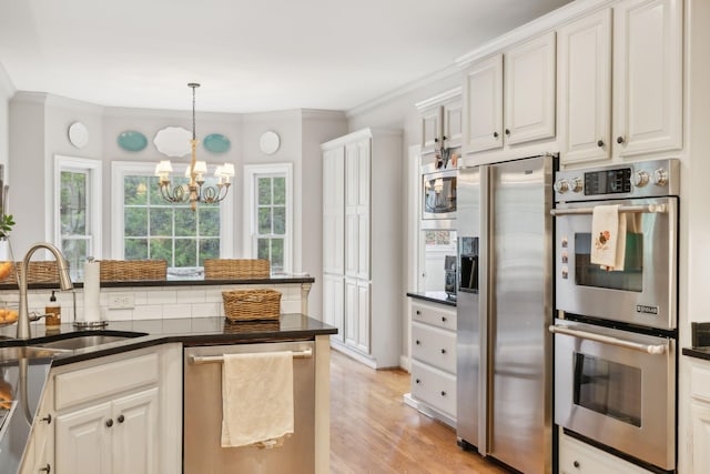 kitchen with white cabinetry, stainless steel appliances, sink, a notable chandelier, and light wood-type flooring