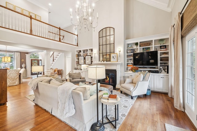 living room featuring a chandelier, a healthy amount of sunlight, a towering ceiling, and hardwood / wood-style floors