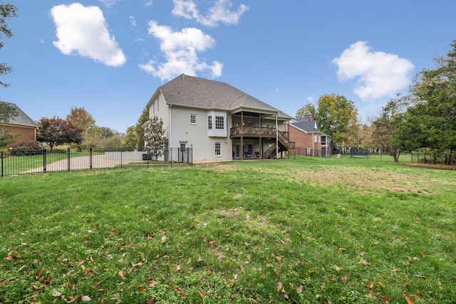 rear view of house featuring a deck, a sunroom, and a lawn