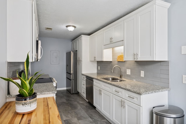 kitchen featuring white cabinets, stainless steel appliances, light stone countertops, and sink