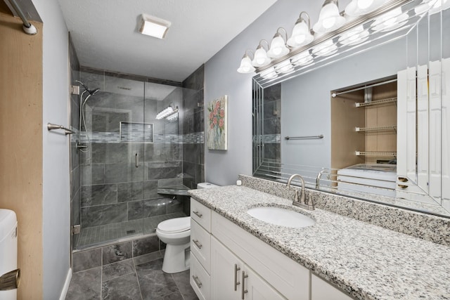 bathroom with vanity, toilet, a shower with shower door, and a textured ceiling