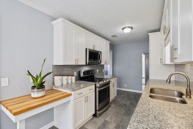 kitchen with backsplash, white cabinetry, sink, and appliances with stainless steel finishes