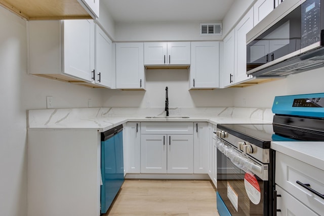 kitchen with light stone countertops, white cabinetry, sink, stainless steel appliances, and light wood-type flooring