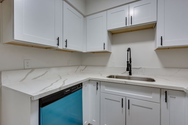 kitchen featuring light stone counters, white cabinetry, stainless steel dishwasher, and sink