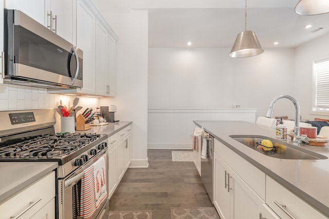 kitchen with pendant lighting, sink, dark hardwood / wood-style flooring, white cabinetry, and stainless steel appliances