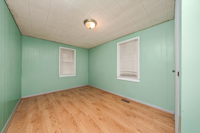 empty room featuring light hardwood / wood-style floors and wood walls