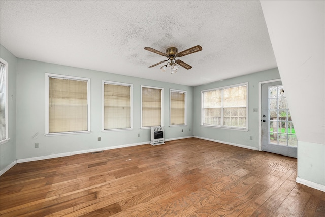 interior space featuring a textured ceiling, heating unit, hardwood / wood-style flooring, and ceiling fan