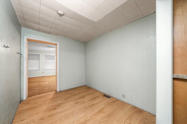 empty room with wooden walls and light wood-type flooring