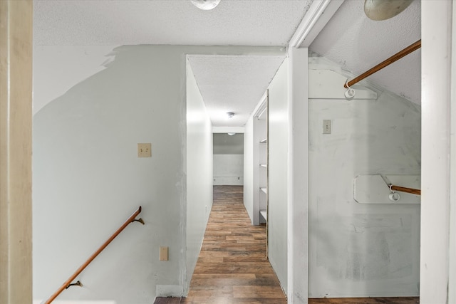 corridor featuring a textured ceiling, lofted ceiling, and hardwood / wood-style flooring