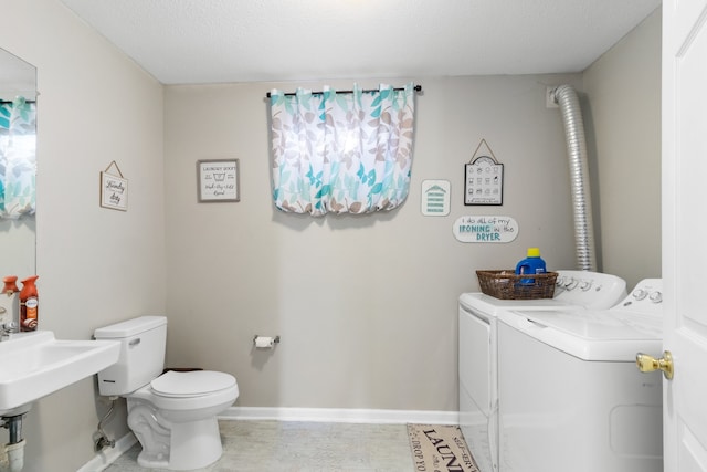 bathroom with a textured ceiling, toilet, and washing machine and clothes dryer