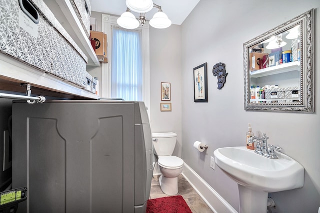 bathroom with sink, a notable chandelier, tile patterned flooring, washer / dryer, and toilet