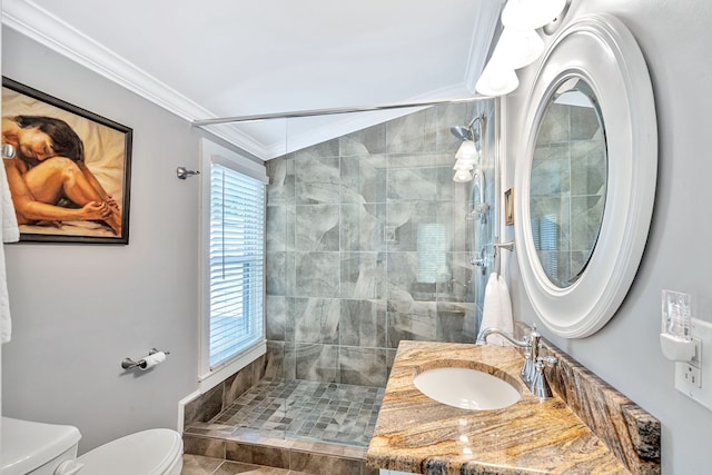 bathroom featuring vanity, tile patterned flooring, toilet, ornamental molding, and a tile shower