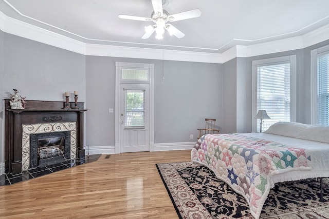 bedroom with a fireplace, ceiling fan, hardwood / wood-style floors, and ornamental molding