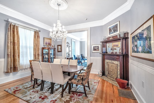 dining space featuring a notable chandelier, light hardwood / wood-style floors, and crown molding