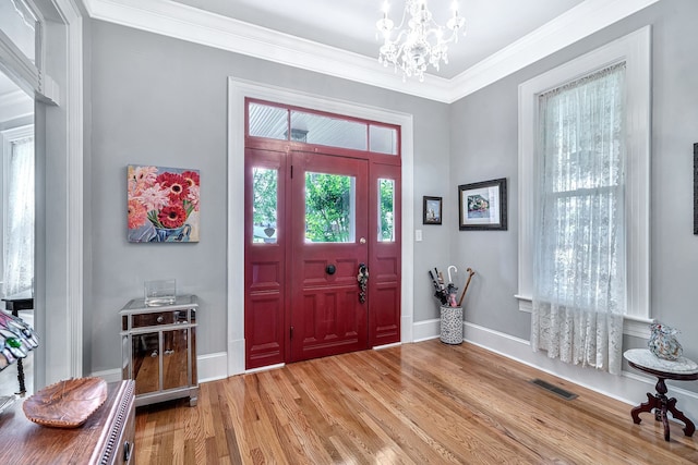 entrance foyer with hardwood / wood-style flooring, a notable chandelier, and crown molding