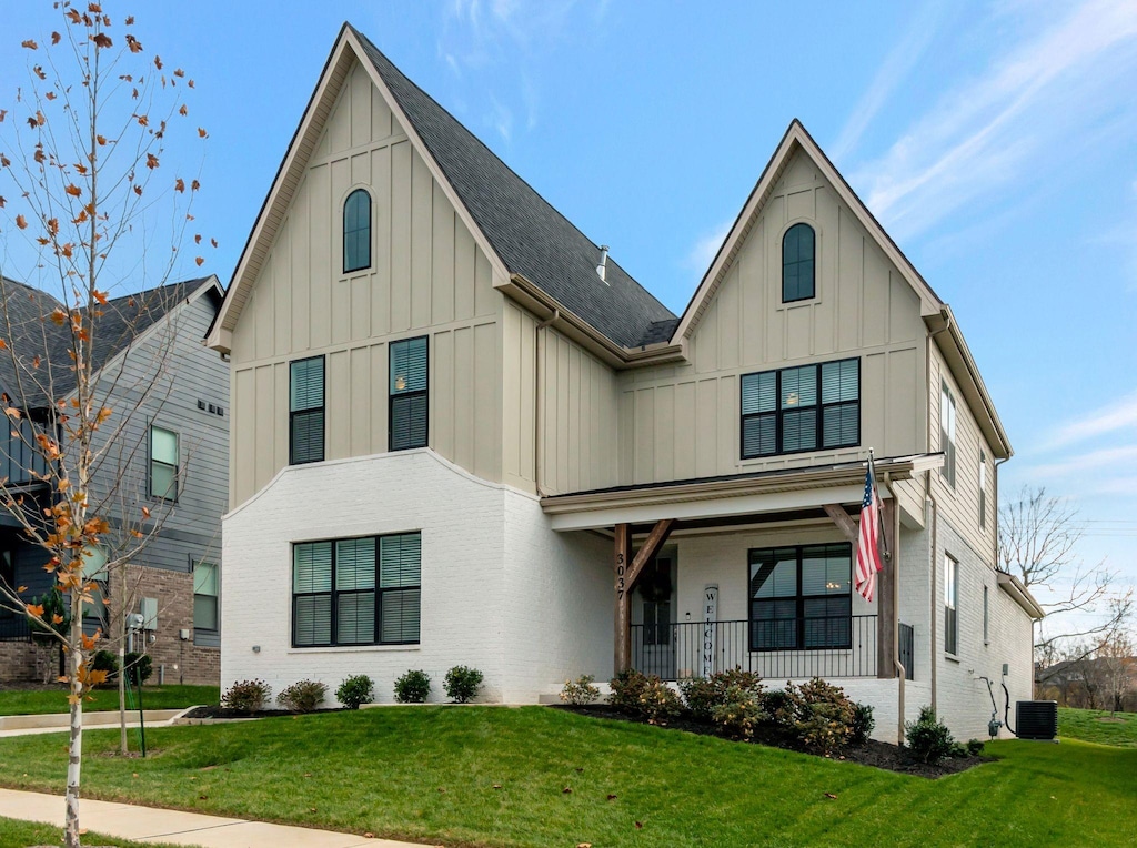 view of front of home featuring central AC unit, covered porch, and a front yard