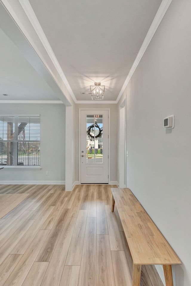 entrance foyer with an inviting chandelier, crown molding, and light hardwood / wood-style flooring