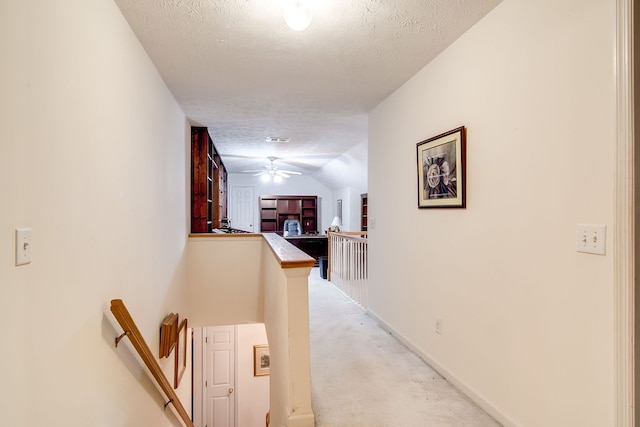 hall featuring lofted ceiling, a textured ceiling, and light carpet