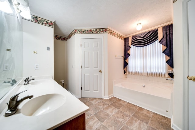 bathroom featuring a bathing tub, vanity, a textured ceiling, and ornamental molding